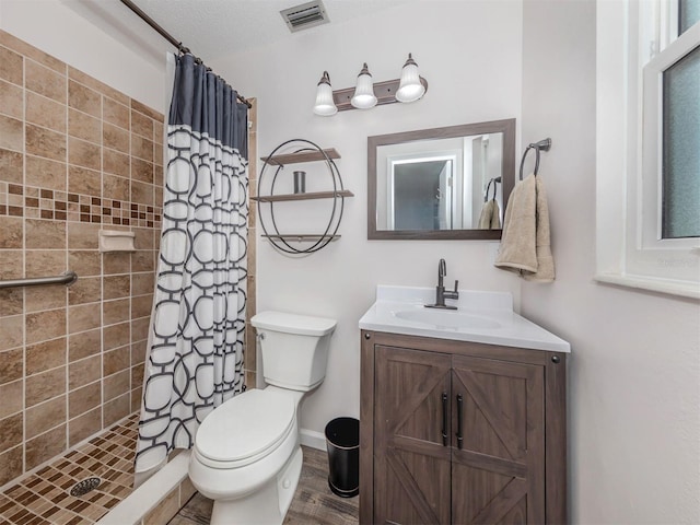 bathroom featuring walk in shower, a textured ceiling, vanity, and toilet