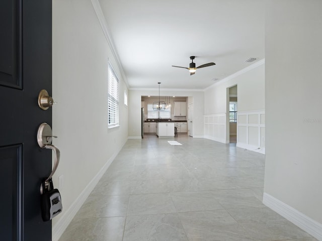 unfurnished living room featuring ceiling fan with notable chandelier and crown molding