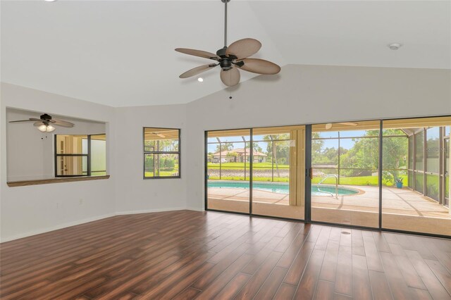 unfurnished room featuring a ceiling fan, a sunroom, vaulted ceiling, wood finished floors, and baseboards