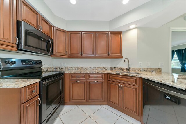 kitchen featuring dishwashing machine, stainless steel microwave, light stone countertops, black electric range, and a sink