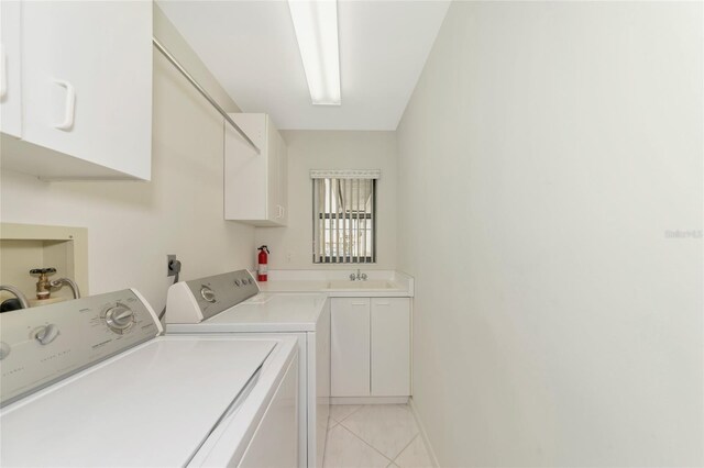 washroom featuring cabinet space, light tile patterned floors, baseboards, washing machine and clothes dryer, and a sink