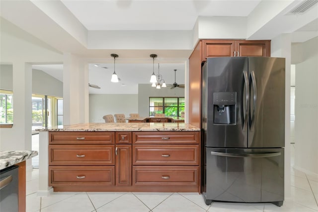 kitchen with visible vents, brown cabinetry, decorative light fixtures, light stone countertops, and black fridge