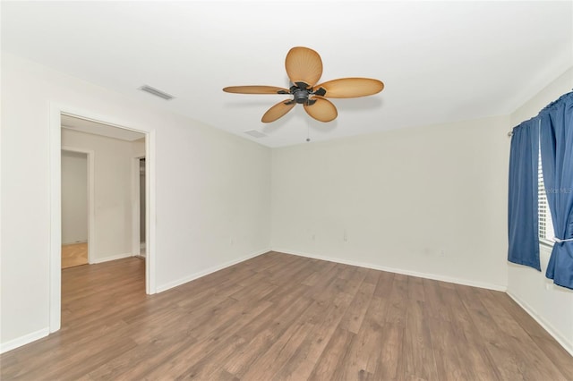 spare room with baseboards, visible vents, and wood finished floors