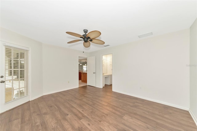 spare room featuring a ceiling fan, visible vents, baseboards, and wood finished floors