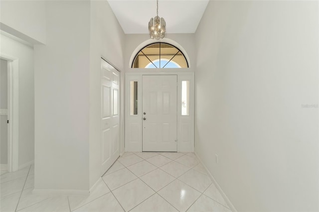 foyer entrance with a notable chandelier, baseboards, and light tile patterned floors