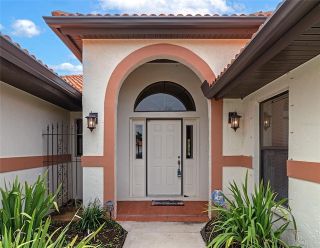 doorway to property featuring a tiled roof and stucco siding