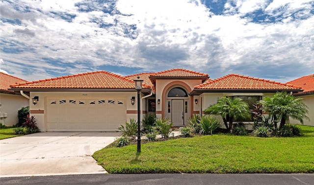 mediterranean / spanish home featuring stucco siding, concrete driveway, an attached garage, a front yard, and a tiled roof