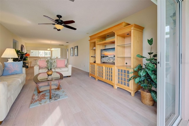 living room featuring ceiling fan with notable chandelier and light hardwood / wood-style floors