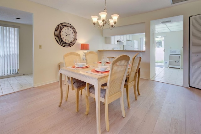 dining space with light wood-type flooring and a chandelier