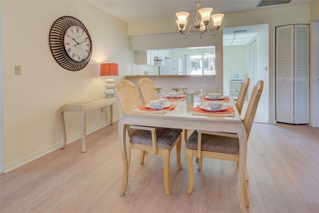 dining room with light hardwood / wood-style floors and a notable chandelier