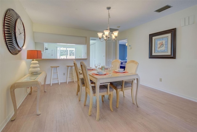 dining room with light wood-type flooring and a chandelier