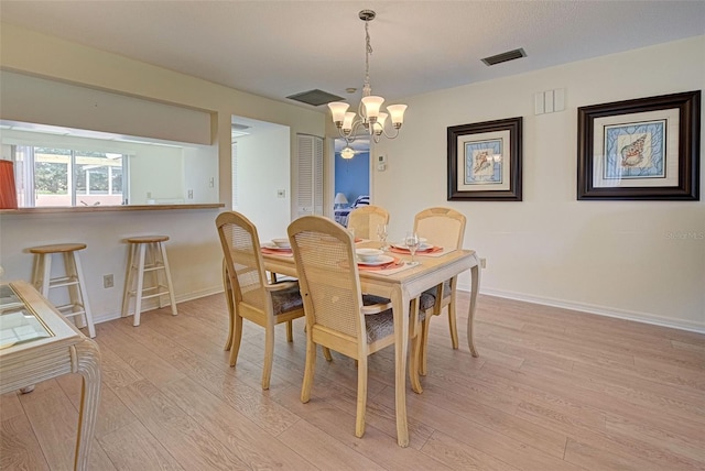 dining room with light wood-type flooring and a chandelier