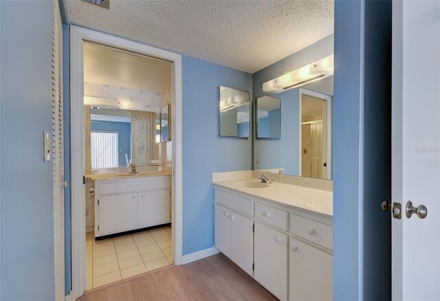 bathroom featuring a textured ceiling, wood-type flooring, vanity, and a shower with door