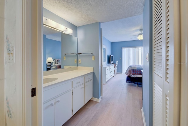 bathroom with ceiling fan, hardwood / wood-style flooring, vanity, and a textured ceiling