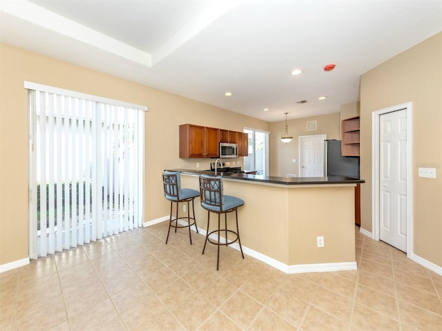 kitchen with stainless steel appliances, hanging light fixtures, kitchen peninsula, light tile patterned floors, and a breakfast bar area