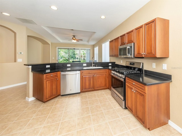 kitchen featuring light tile patterned floors, kitchen peninsula, stainless steel appliances, a tray ceiling, and sink