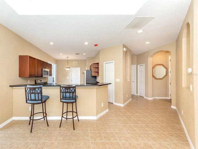 kitchen featuring pendant lighting, kitchen peninsula, a kitchen bar, sink, and appliances with stainless steel finishes