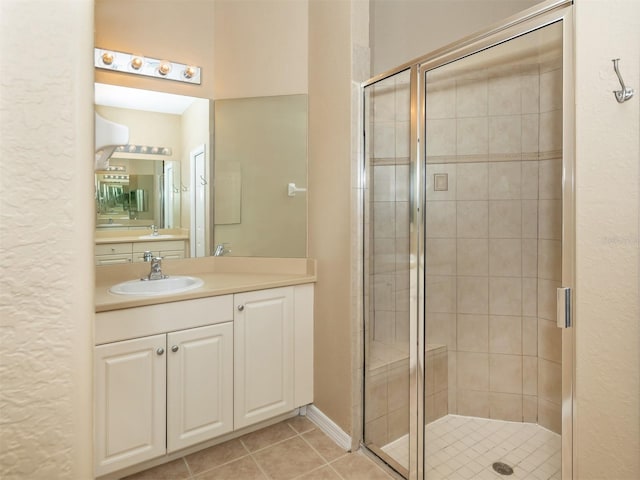 bathroom with a shower with shower door, vanity, and tile patterned flooring