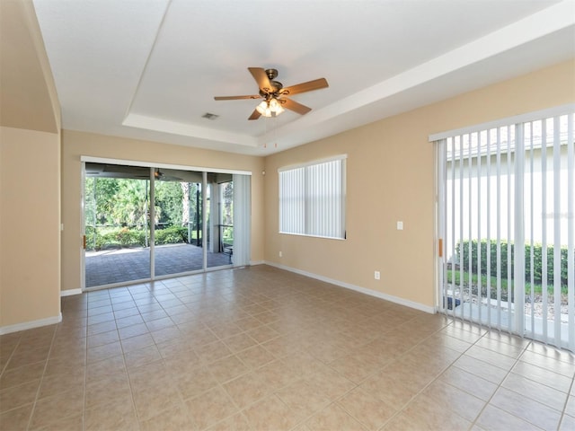 tiled spare room featuring ceiling fan and a raised ceiling