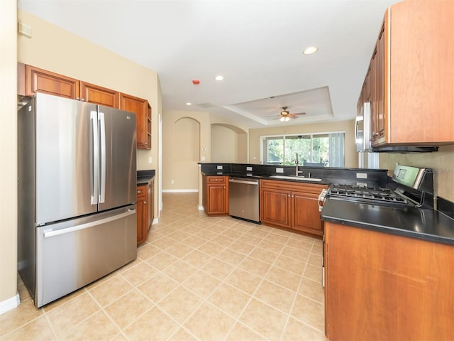 kitchen with ceiling fan, appliances with stainless steel finishes, tasteful backsplash, a tray ceiling, and sink