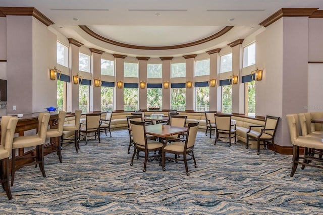 carpeted dining area featuring plenty of natural light, a raised ceiling, and ornamental molding