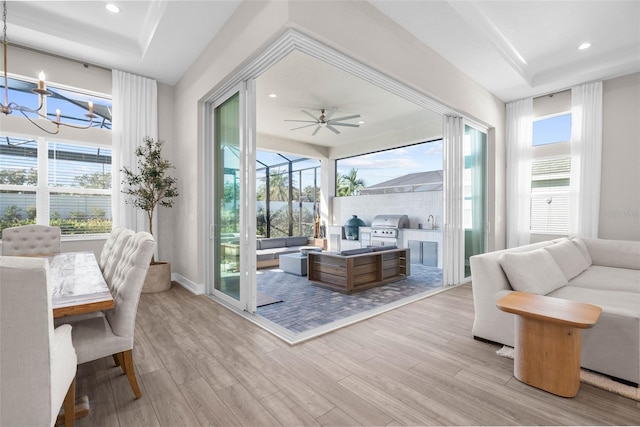 interior space featuring ceiling fan with notable chandelier, a healthy amount of sunlight, and a tray ceiling