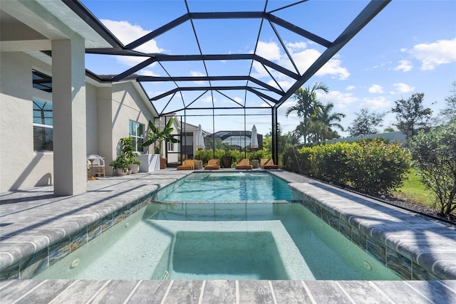 view of swimming pool with glass enclosure, an in ground hot tub, and a patio