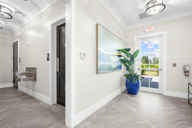 interior space featuring wooden walls, crown molding, and light parquet floors