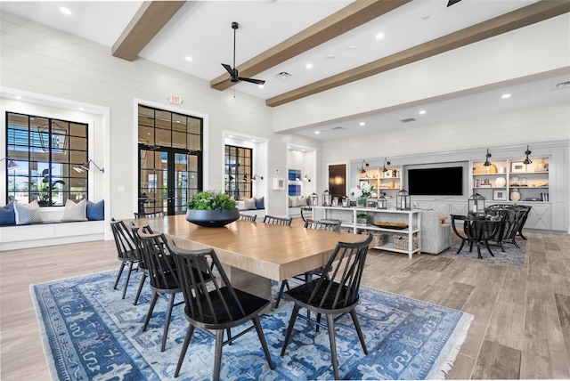 dining area featuring ceiling fan, french doors, a high ceiling, light hardwood / wood-style flooring, and beamed ceiling