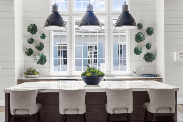 kitchen featuring light stone countertops, wood-type flooring, and wooden walls