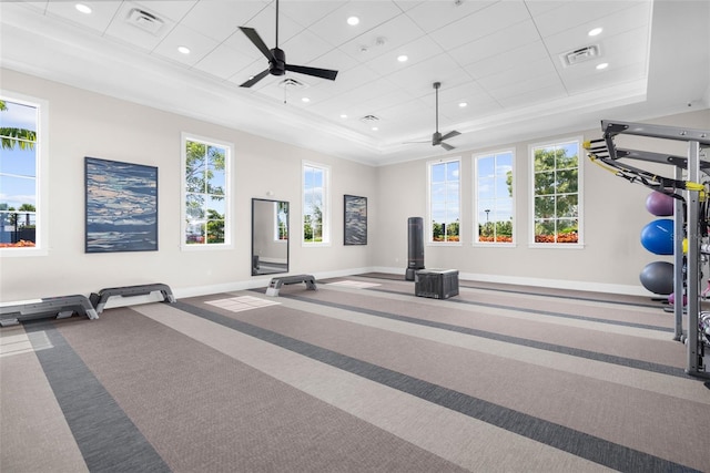 workout room featuring carpet, plenty of natural light, ceiling fan, and a tray ceiling