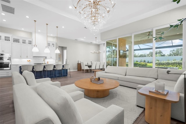 living room featuring wood-type flooring, crown molding, and a notable chandelier