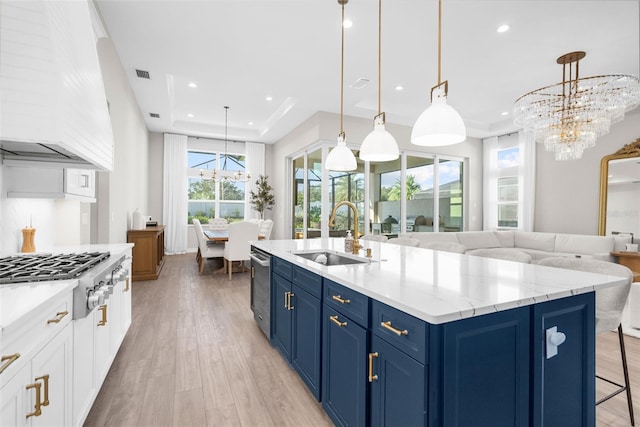 kitchen with custom exhaust hood, blue cabinets, sink, decorative light fixtures, and light hardwood / wood-style floors