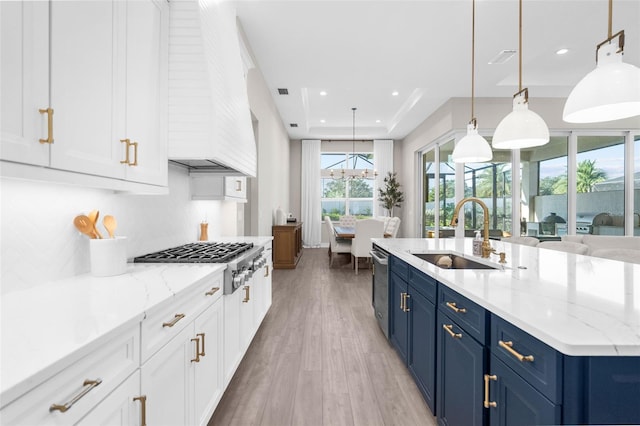 kitchen with sink, hanging light fixtures, blue cabinets, light hardwood / wood-style floors, and white cabinets