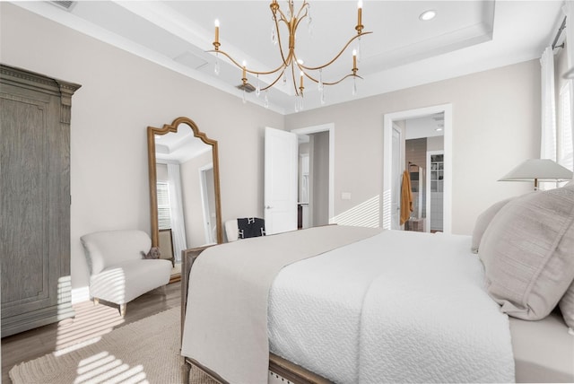 bedroom with hardwood / wood-style flooring, multiple windows, a tray ceiling, and a chandelier