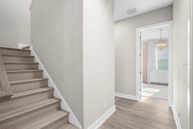 staircase with a notable chandelier and hardwood / wood-style flooring