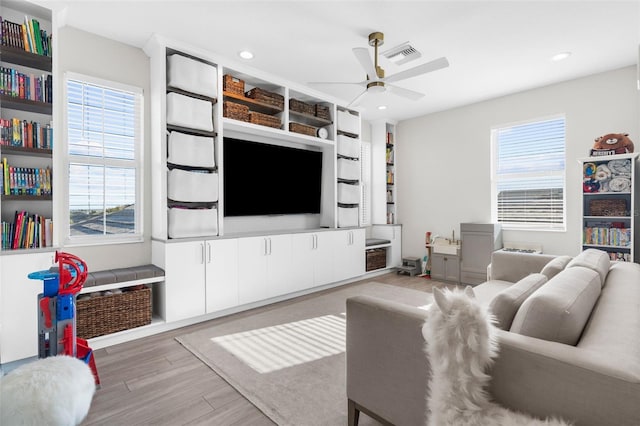 living room featuring a wealth of natural light, light hardwood / wood-style flooring, and ceiling fan