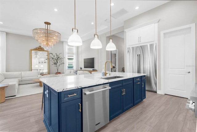 kitchen with sink, hanging light fixtures, light wood-type flooring, blue cabinetry, and stainless steel appliances