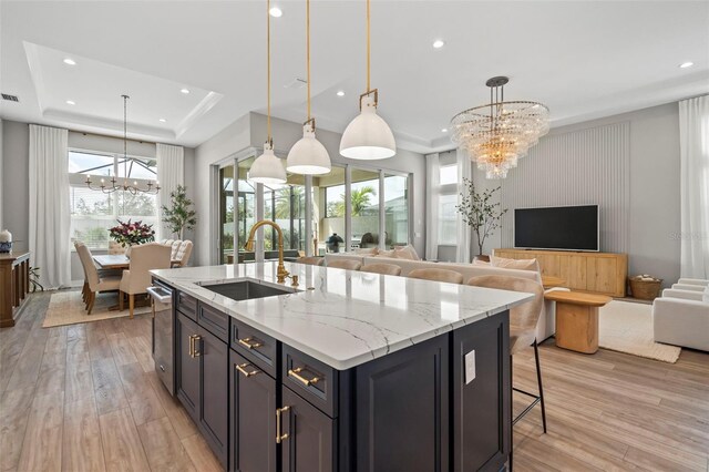 8209 Redonda Loop, Lakewood Ranch, FL 34202 - kitchen featuring a kitchen breakfast bar, a tray ceiling, a sink, light wood finished floors, and a notable chandelier
