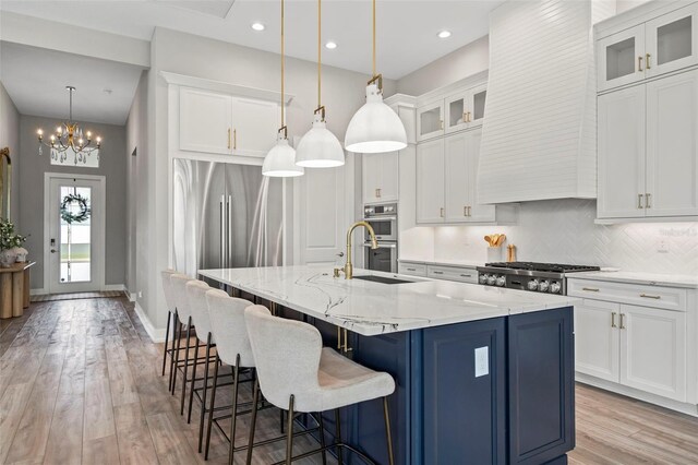 8209 Redonda Loop, Lakewood Ranch, FL 34202 - kitchen featuring decorative backsplash, an island with sink, light wood-style flooring, and stainless steel appliances