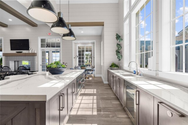 8209 Redonda Loop, Lakewood Ranch, FL 34202 - kitchen featuring decorative light fixtures, light wood-type flooring, a sink, beam ceiling, and light stone countertops