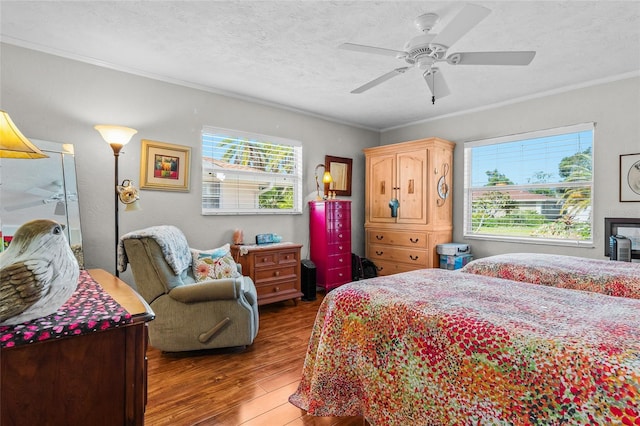 bedroom with ceiling fan, ornamental molding, dark hardwood / wood-style flooring, and a textured ceiling