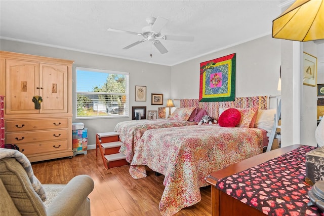 bedroom with ceiling fan, ornamental molding, and wood-type flooring