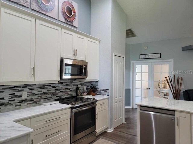 kitchen featuring light stone counters, white cabinets, decorative backsplash, appliances with stainless steel finishes, and dark hardwood / wood-style flooring