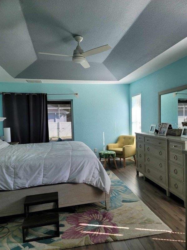 bedroom with wood-type flooring, multiple windows, and ceiling fan