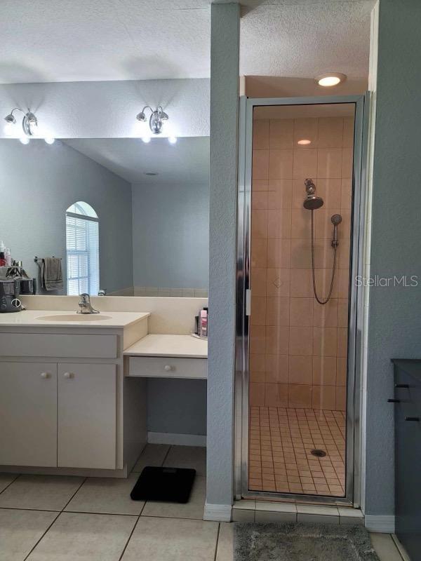 bathroom featuring a textured ceiling, vanity, tile patterned floors, and an enclosed shower