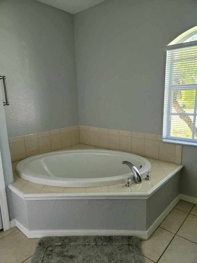 bathroom with tile patterned floors and a relaxing tiled tub