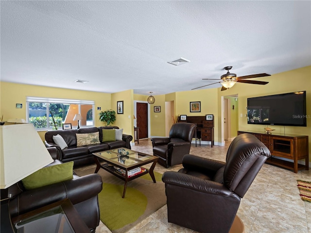 living room with ceiling fan and a textured ceiling