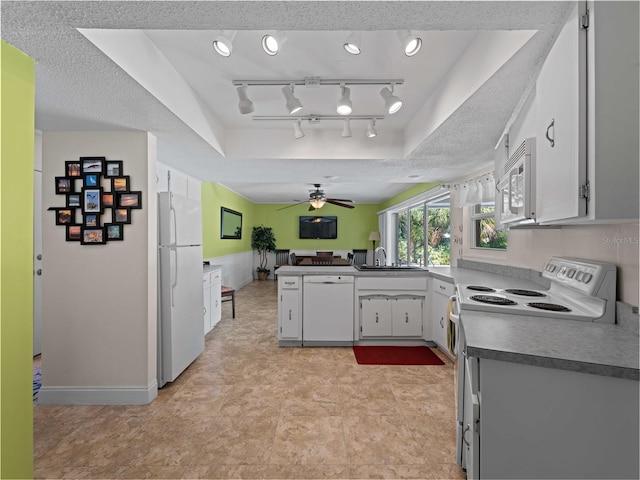 kitchen featuring a tray ceiling, a textured ceiling, white cabinetry, white appliances, and ceiling fan