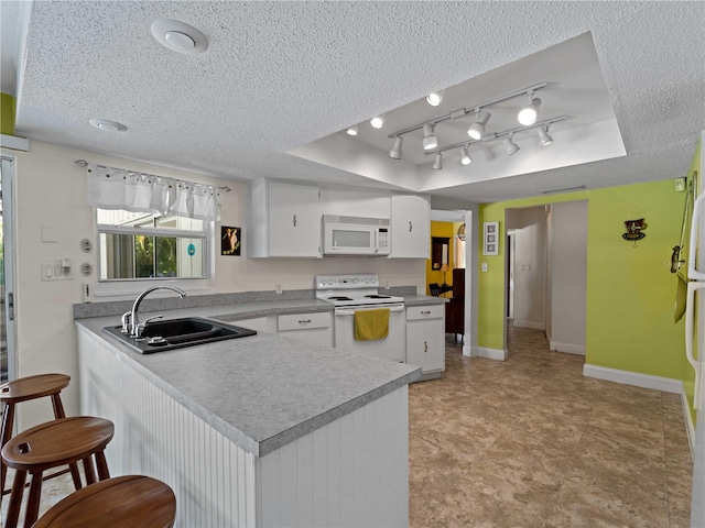 kitchen with white cabinets, white appliances, a raised ceiling, and sink